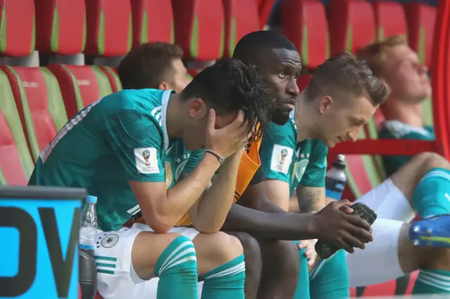 Mesut Ozil has his hands on his head on the bench for Germany