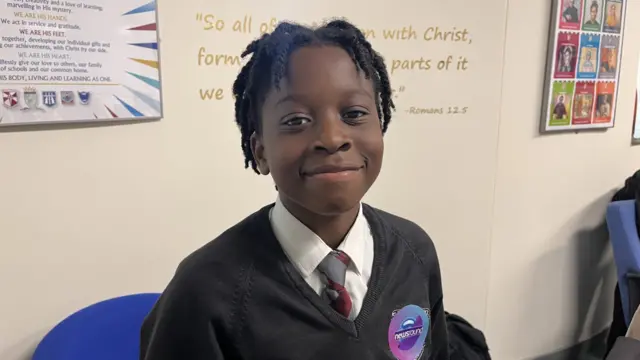 A child in school uniform pictured smiling in a classroom