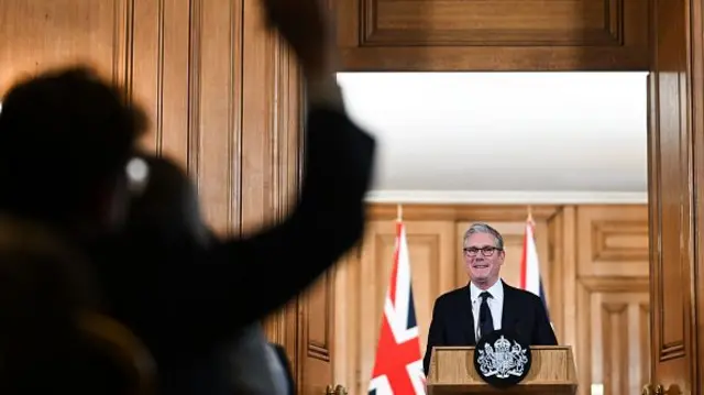 Keir Starmer stands at a wooden podium