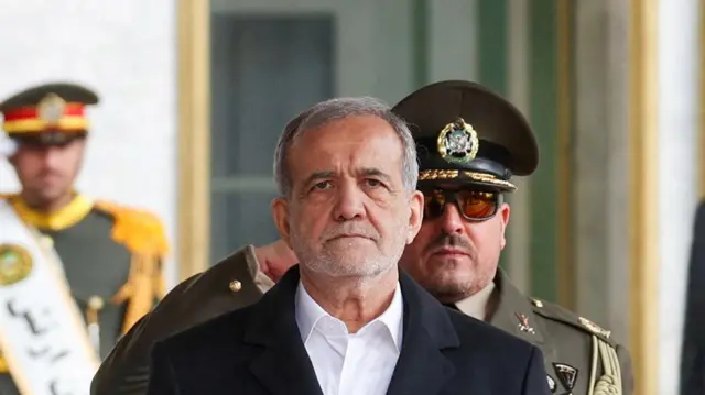Masoud Pezeshkian with a saluting guard stood behind him