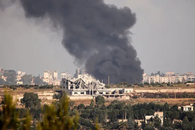 Large plumes of smoke rise near damaged buildings