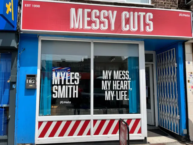 A barbers called "messy cuts" tih Myles Smith's name and album title written on the window.