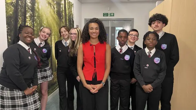 A woman stands with schoolchildren.