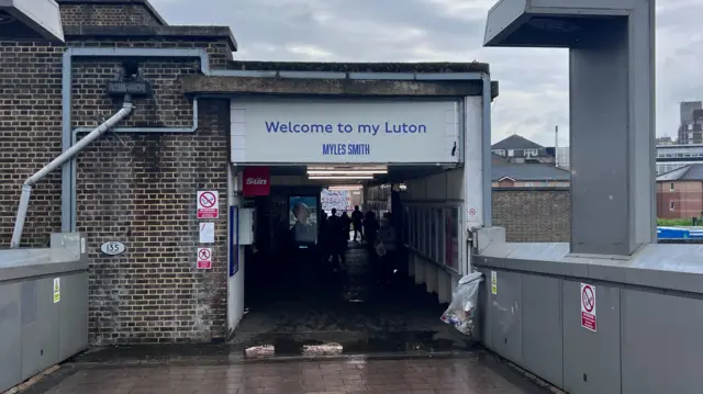 A sign over the entrance to Luton's train station which reads "Welcome to my Luton, Myles Smith".