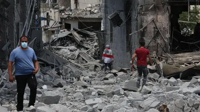 a few people standing on top of piles of building rubble