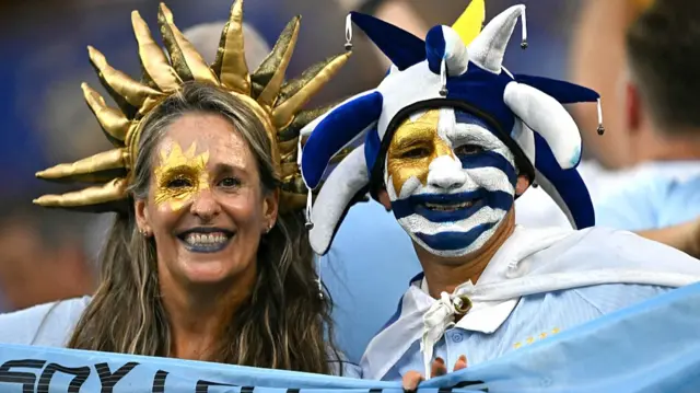 A female and a male Uruguay fan with gold, blue and white facepaints