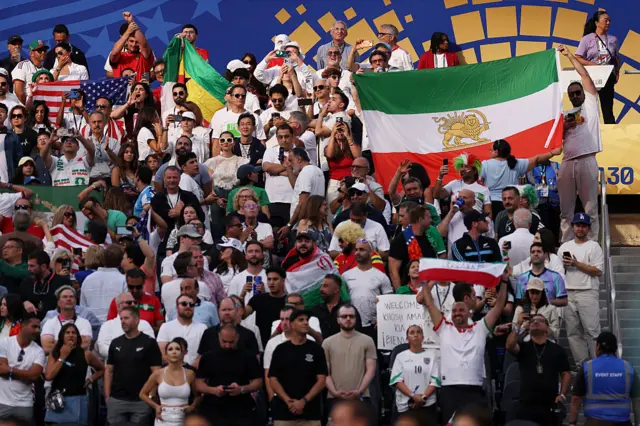 Iran fans holding a lion and sun flag inside the stadium