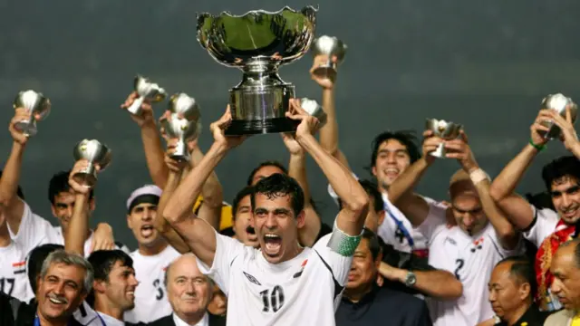 Iraq's captain Younis Mahmoud (C) holds up the winning trophy as he along with teammates celebrate