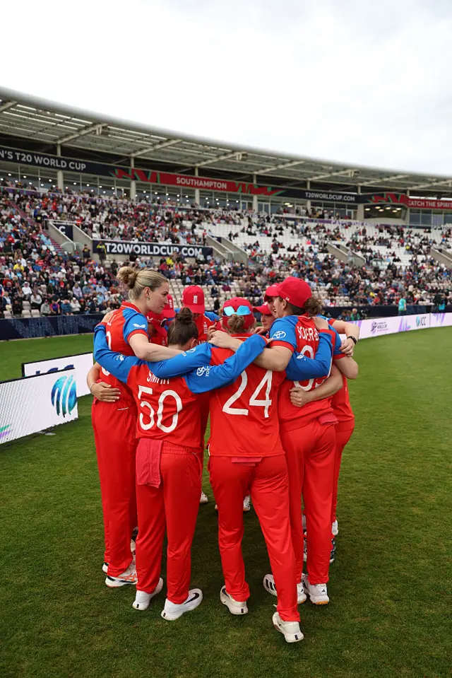 England team in a huddle facing the crowd.