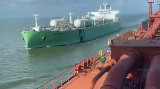 A screengrab from a video showing large green tanker is seen sailing past another ship