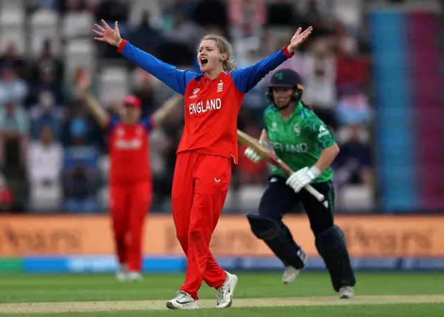 Charlie Dean with her arms aloft and mouth open claiming for a wicket