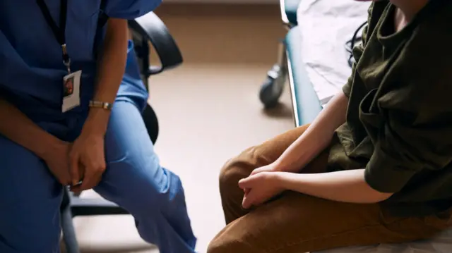High angle view of doctor with patient sitting on examination table in clinic.