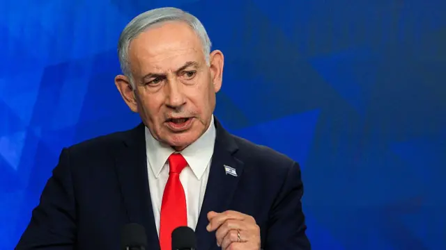 Benjamin Netanyahu in a black suit with red tie.