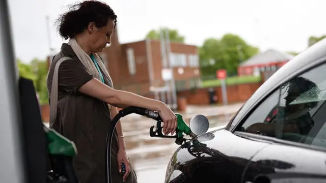 A woman puts fuel in her car at a filling station.