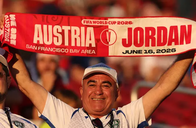 A fan holding a Austria and Jordan half and half scarf