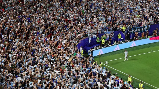 Lionel Messi approaches fans at the corner flag