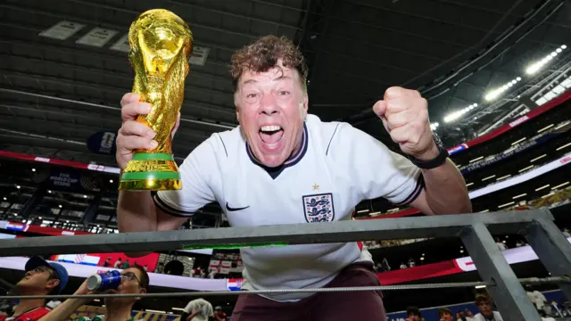 England fan Andy Milne poses in the stands with a World Cup replica trophy