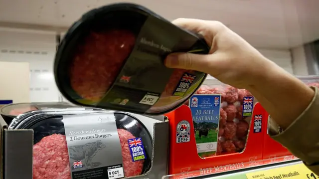A customer selects a packet of 100% British Farmed Aberdeen gourmet beef burgers at a supermarket.