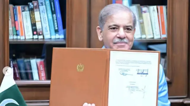 A photo of Pakistani Prime Minister Shehbaz Sharif holding up a photo of a signed Memorandum of Understanding