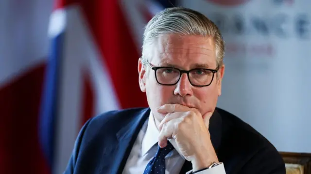 Prime Minister Keir Starmer with his hand on his chin and a Union Jack in the background.