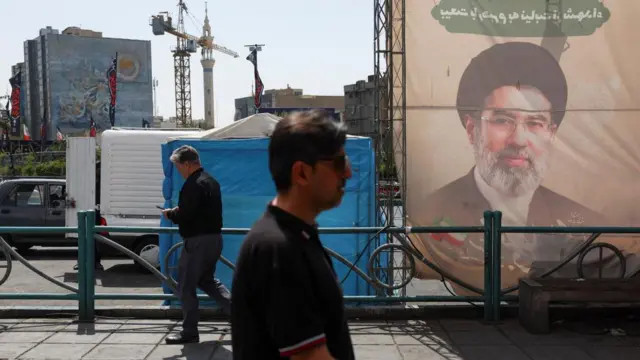 People walk past a banner with a picture of Iran's Supreme Leader, Mojtaba Khamenei, in Tehran