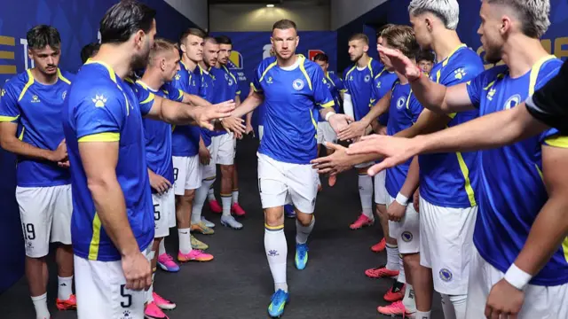 Edin Dzeko high-fives his team-mates as he heads out on to the pitch