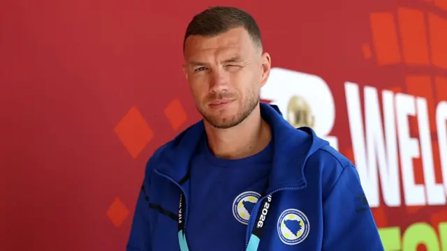 Edin Dzeko winks at the camera as he walks into the stadium