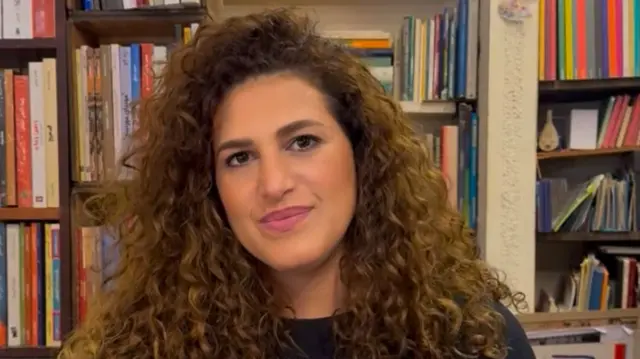 Lana Halabi is shown smiling in front of a bookcase