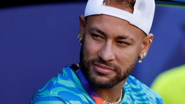 Neymar looks on wearing a white cap and blue shirt
