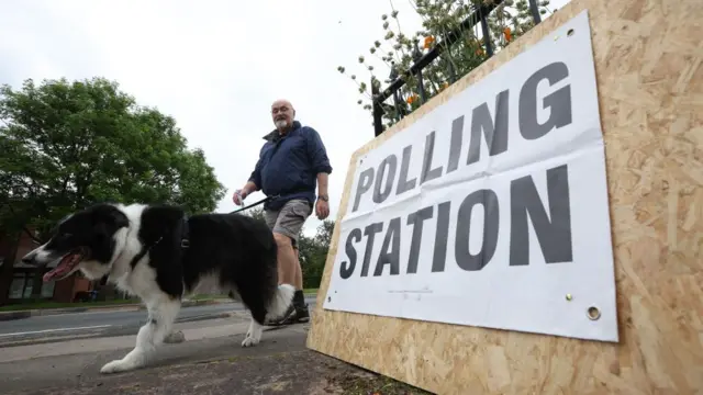 A person at the St Aidan's Parish Centre polling station with their dog in Wigan