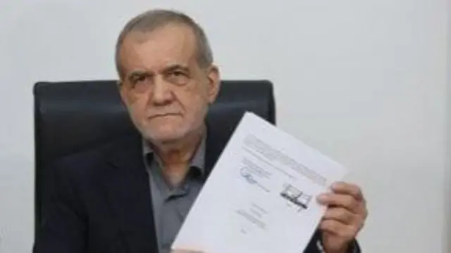 Iranian president Masoud Pezeshkian holding up a signed copy of the memorandum of understanding