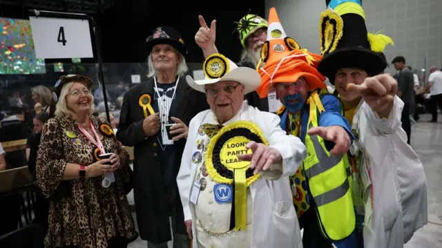 Monster Raving Loony Party candidate Howling Laud Hope (C) and supporters attend the vote count for the Makerfield by-election in Wigan, Britain, 18 June 2026.