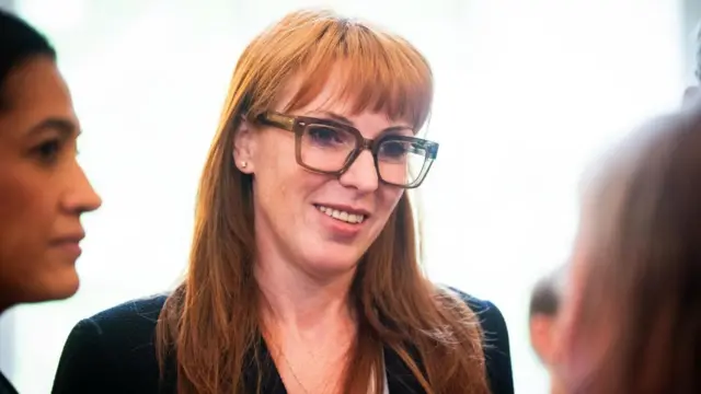Angela Rayner pictured smiling as she speaks to two people.