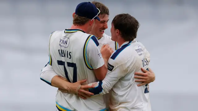 Matt Revis, James Wharton and Dom Bess all hug in celebration after Bess takes a wicket for Yorkshire