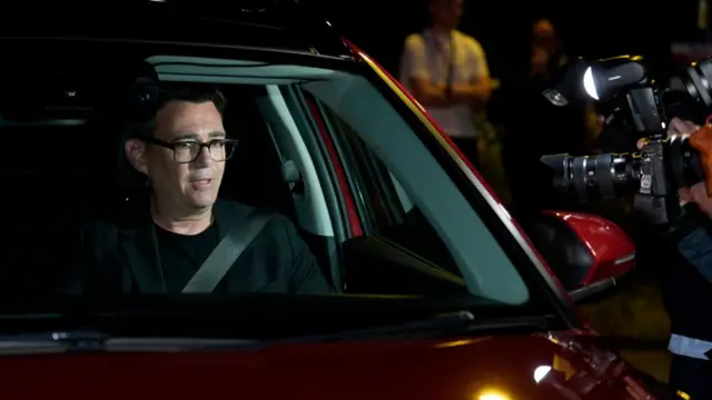 Andy Burnham sits in a red car as he leaves The Edge in Wigan after winning the Makerfield by-election