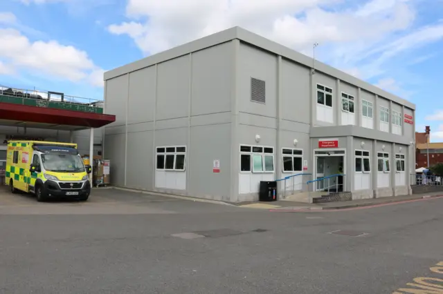 The outside of the A&E department at Bedford Hospital, with one ambulance parked outside.