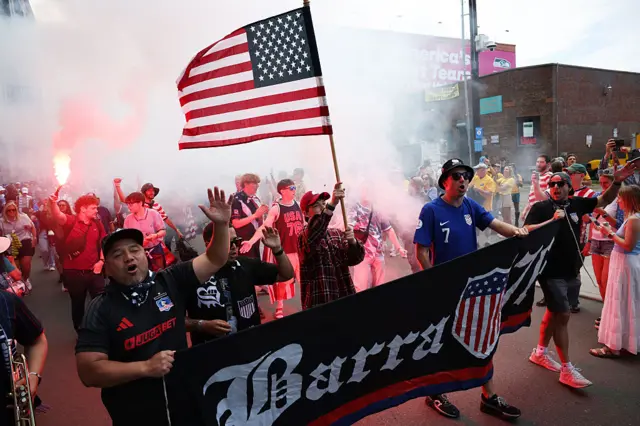 USA fans march with banners, flags and flares