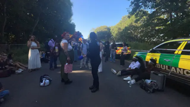 An image showing emergency vehicles and people sitting around on a road