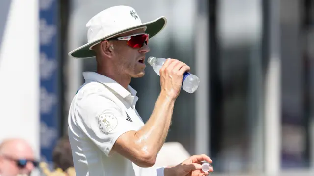 Notts Fergus O'Neill in a sun hat swigs from a bottle of water