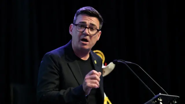 Andy Burnham speaking at a lectern