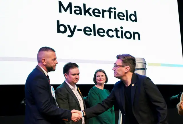 Burnham shaking hands with Reform UK's Robert Kenyon, who finished second