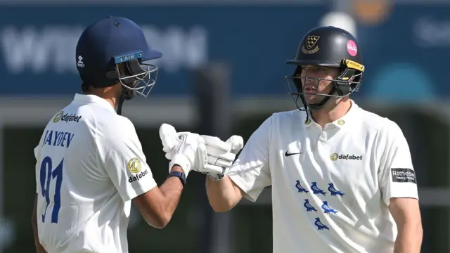 Jaydev Unadkat (left) punches gloves with Sussex team-mate James Coles