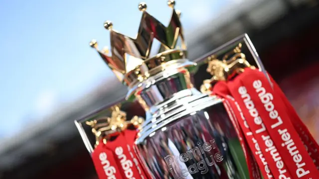 A detailed view of the Premier League trophy, dressed in red ribbons,