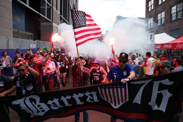 USA fans march with banners, flags and flares
