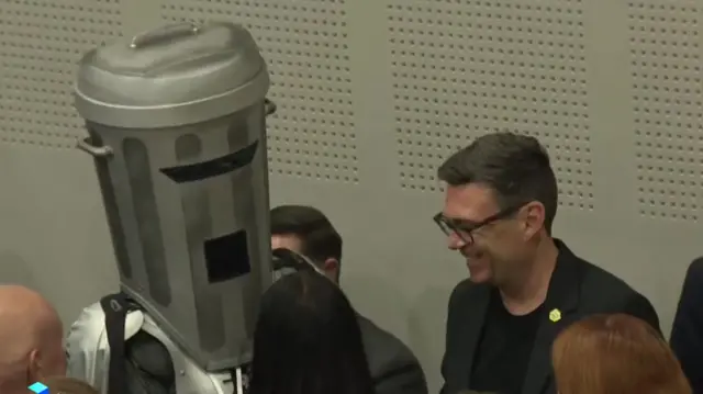 Andy Burnham smiles as he speaks to fellow candidate Count Binface