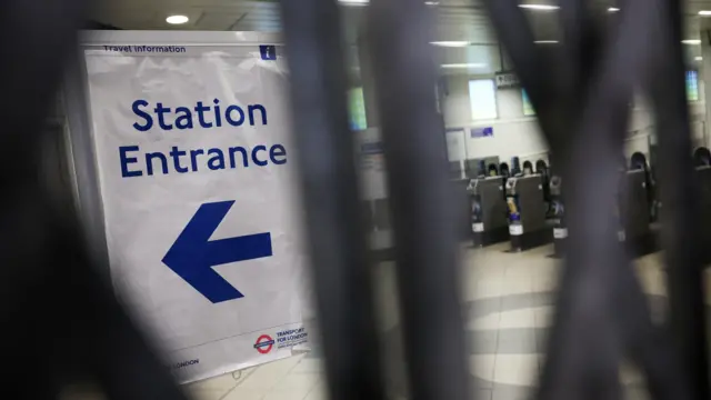 A station sign behind a closed gate