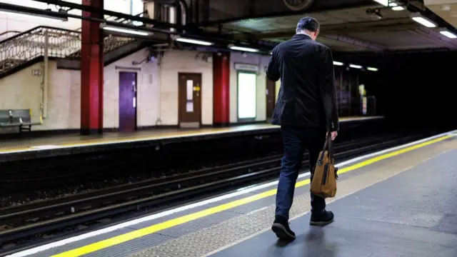 A man walking along an empty Tube platform
