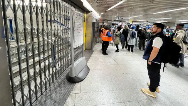 A man stands outside a closed staircase on the London Underground network