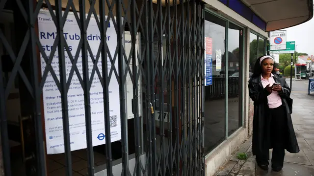 A woman stands outside closed Underground station gates