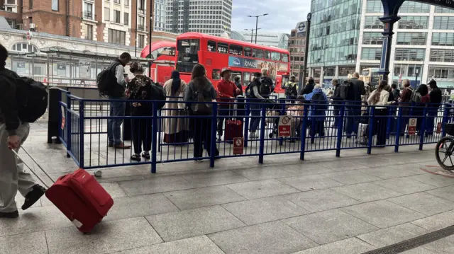 People standing in a queue for taxis at London Victoria station